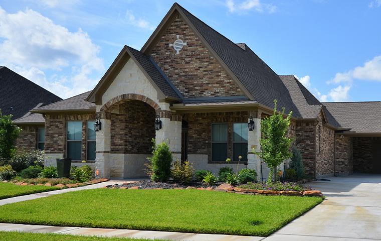 A home with a brick exterior and beautiful landscaping by Trees Hurt Too.