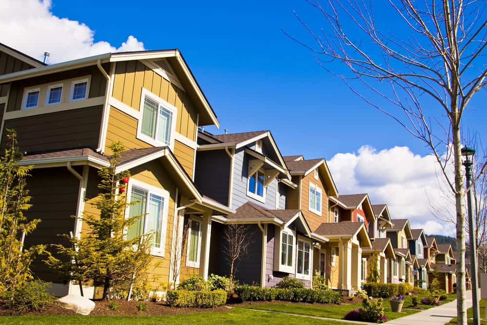 A row of colorful suburban houses with well-kept lawns, managed seamlessly by HOAs, sits under a clear blue sky. A row of colorful suburban houses with well-kept lawns, managed seamlessly by HOAs, sits under a clear blue sky.